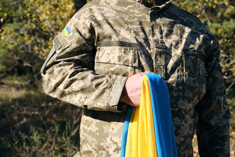 ukrainian-soldier-holds-in-his-hand-the-yellow-blue-flag-of-the-state-he-pressed-his-hand-to-his-chest_116441-6964